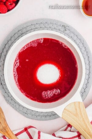 sugar added to raspberry juice in a saucepan