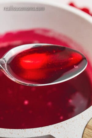 close up of a spoonful of raspberry syrup over the saucepan