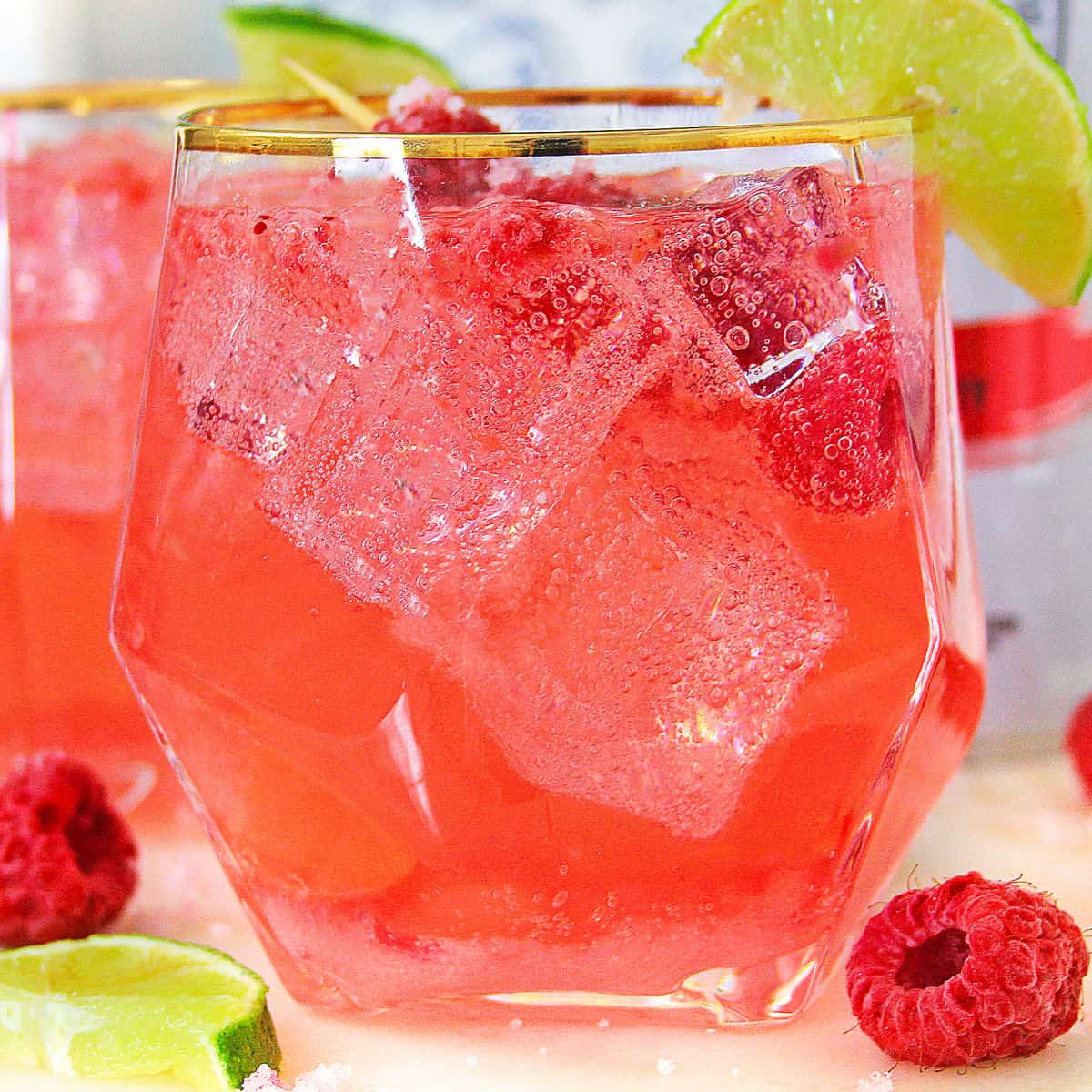 square image close up of raspberry white claw cocktail with limes and raspberries