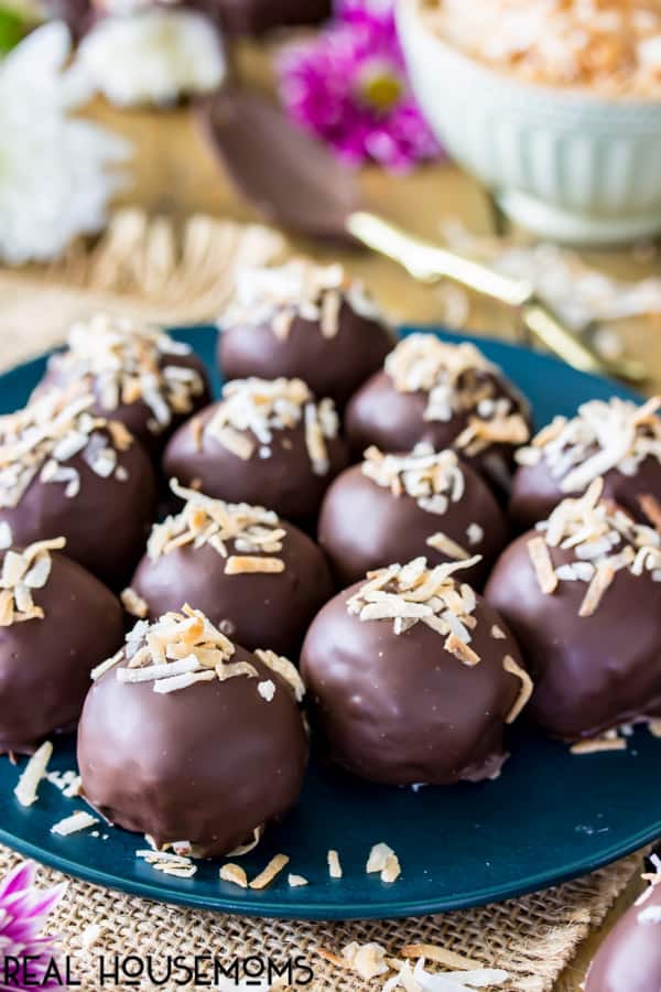 Chocolate covered coconut cream truffles topped with toasted coconut on a serving plate