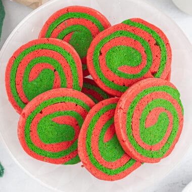 square image of red & green pinwheel cookies arranged on a plate