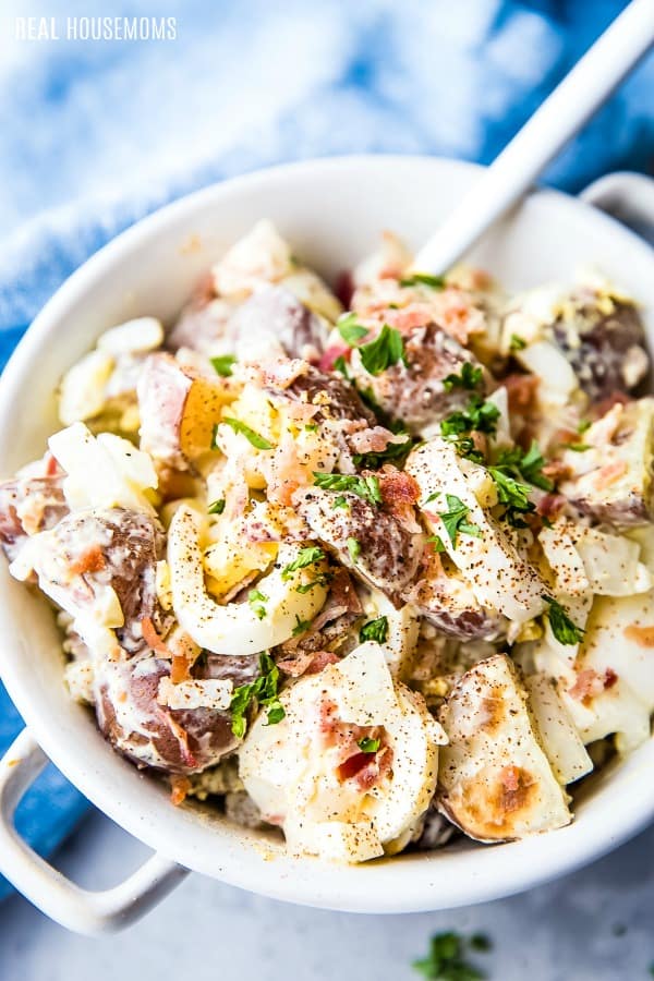 red potato salad in a bowl topped with bacon and parsley