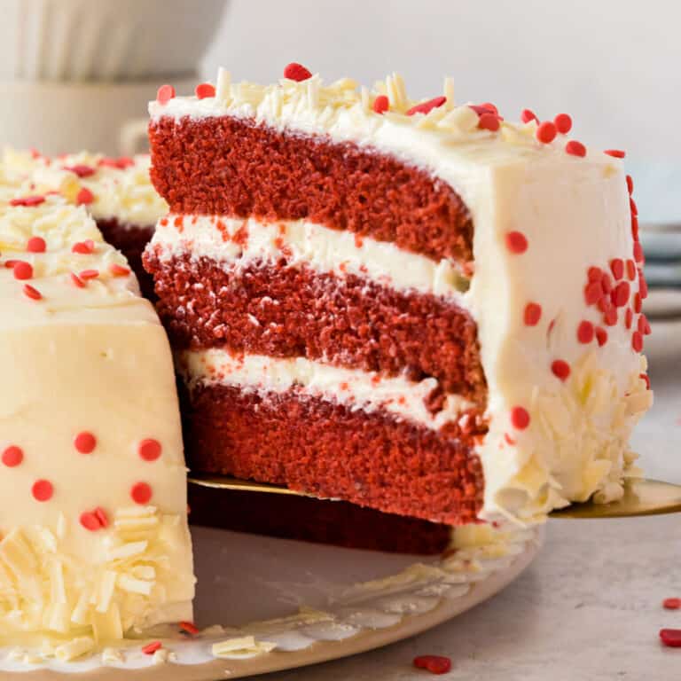 square iage of a cake serve lifting a slice of red velvet cake from the cake