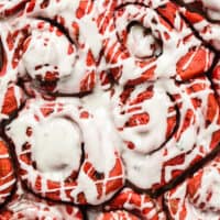 image of red velvet sweet rolls with icing in a round pan with the title of the post on top of the image in blue and black lettering