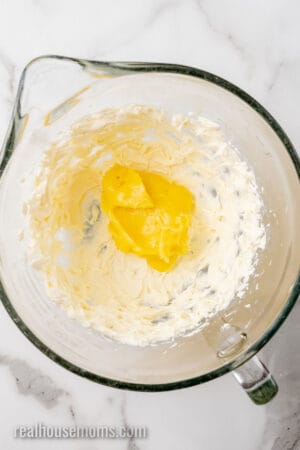 lemon curd added to beaten cream cheese in a glass mixing bowl