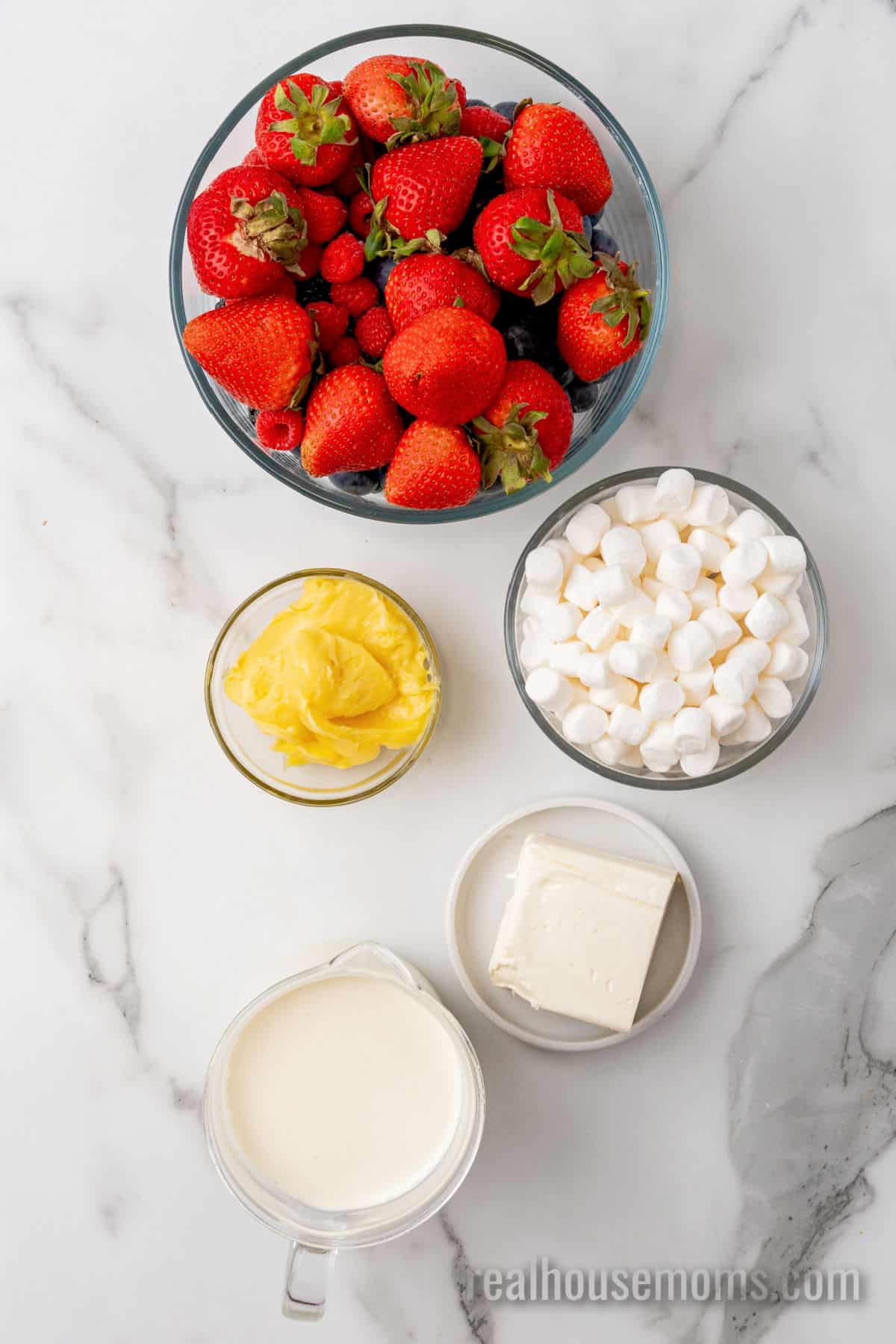 ingredients to make red white and blue cheesecake salad in bowls on a counter