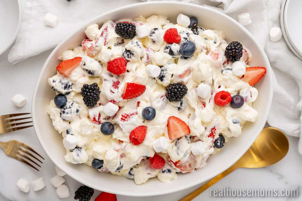 looking down at red white and blue cheesecake salad topped with fresh berries in a serving bowl