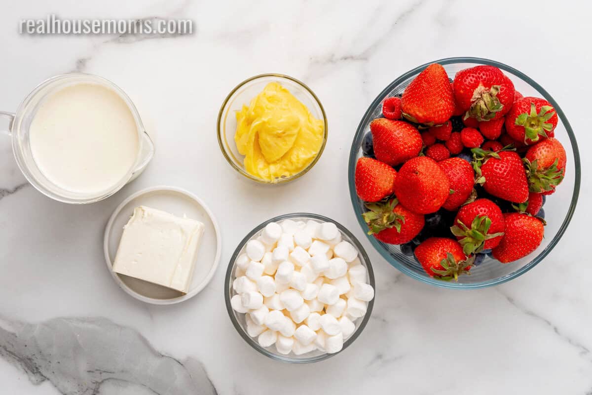 ingredients to make red white and blue cheesecake salad in bowls on a counter