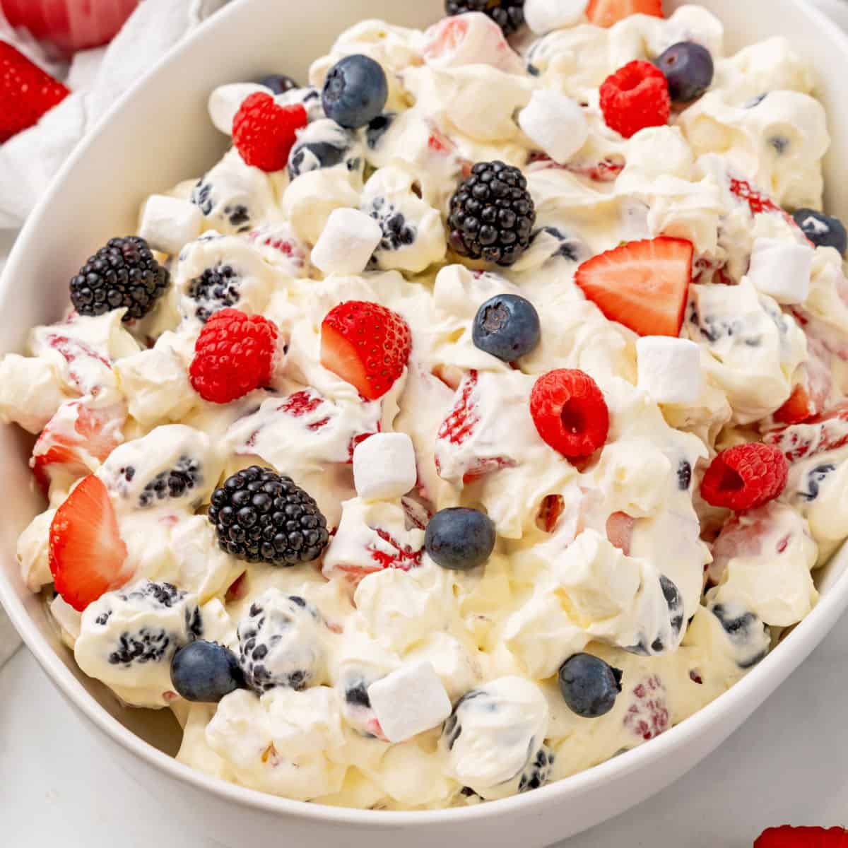 square image of red white and blue cheesecake salad in a white serving bowl