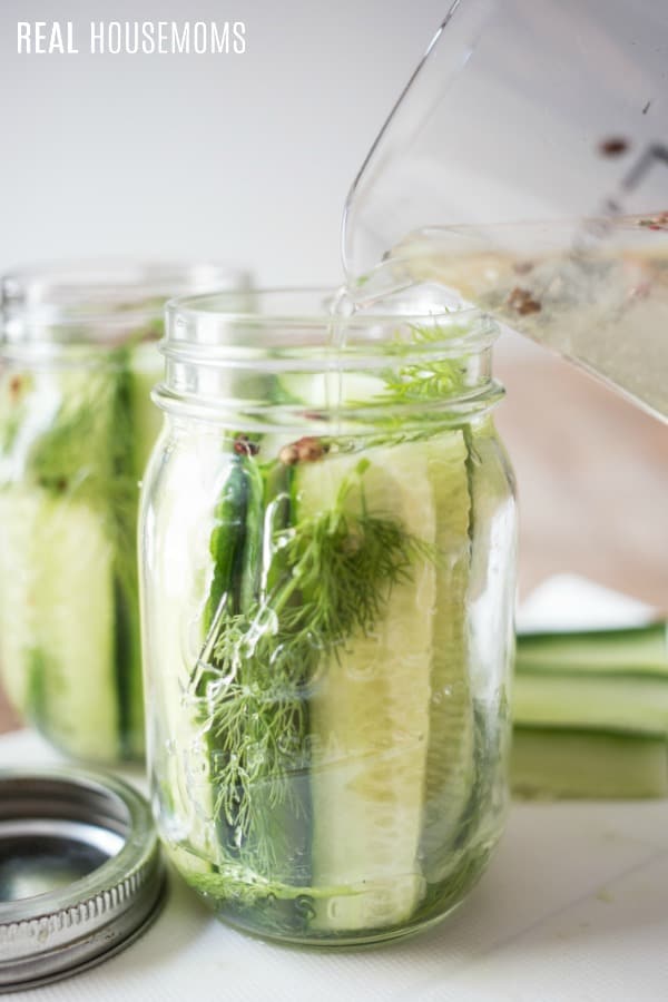 brine being poured into mason jars of cucumbers for refrigerator pickles