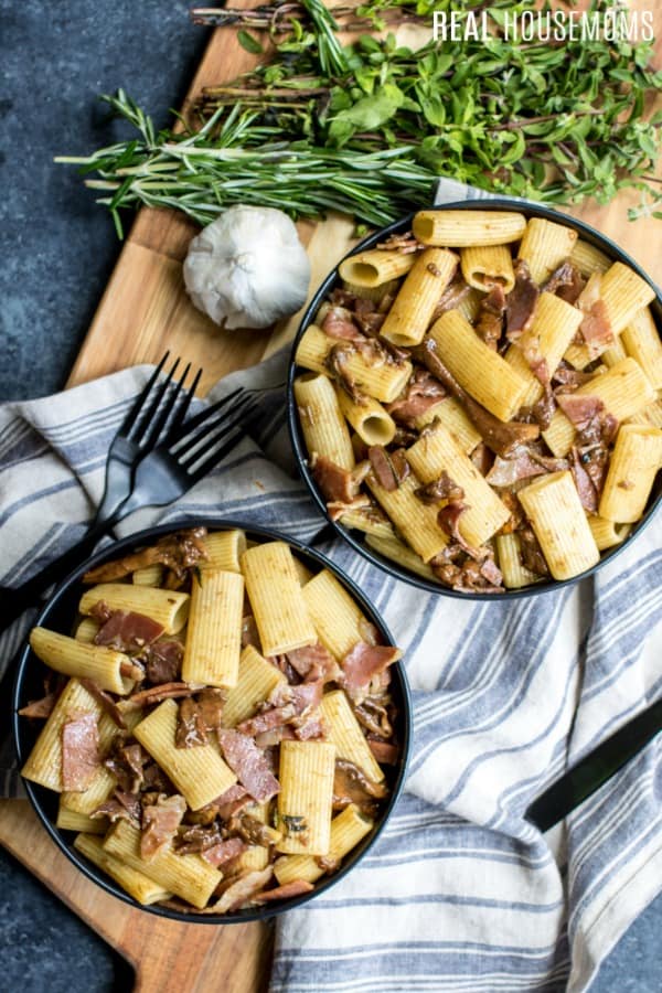 overhead picture of rigatoni pasta with mushrooms and prosciutto in bowls with garlic and herbs