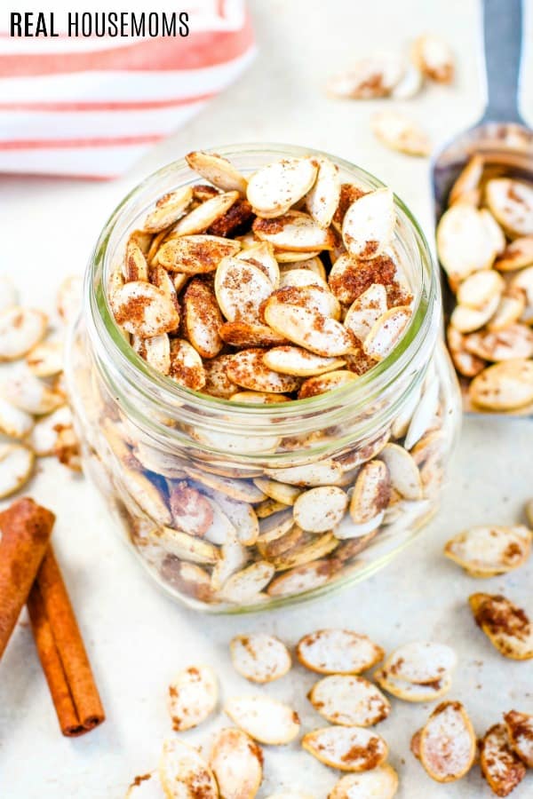roasted pumpkin seeds in a mason jar with more seeds scattered on the counter