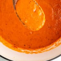 roasted red pepper sauce on a wooden spoon over the skillet with recipe name at the bottom