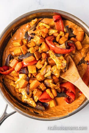 roasted vegetables added to the skillet of indian curry sauce