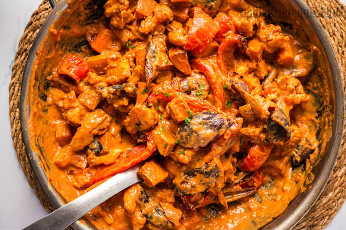 serving spoon in a skillet of roasted vegetable curry