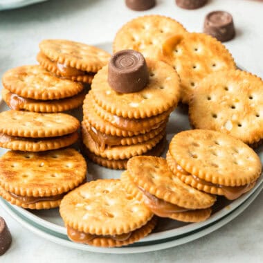 square image of rolo stuffed ritz crackers arranged on a plate with a rolo on top of the center treat