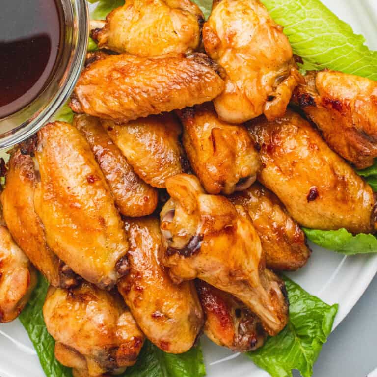square image of root beer chicken wings piled on lettuce on a plate