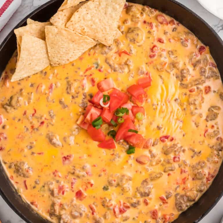 square image of rotel dip in a cast iron skillet with diced tomatoes and green onion on top