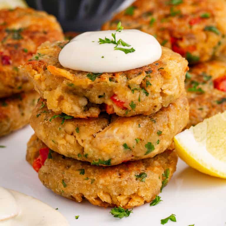 square image of a stack of salmon croquettes with sauce and parsley on top