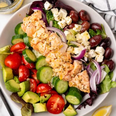 square image of a salmon salad in a bowl next to lemon wedges