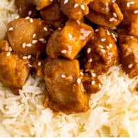 sesame chicken served over white rice with recipe name at the bottom