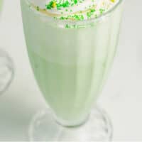 shamrock shake with whipped cream green sprinkles, and a cherry with recipe name at bottom