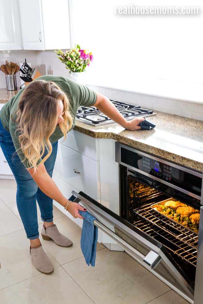 woman checking on dinner in the oven