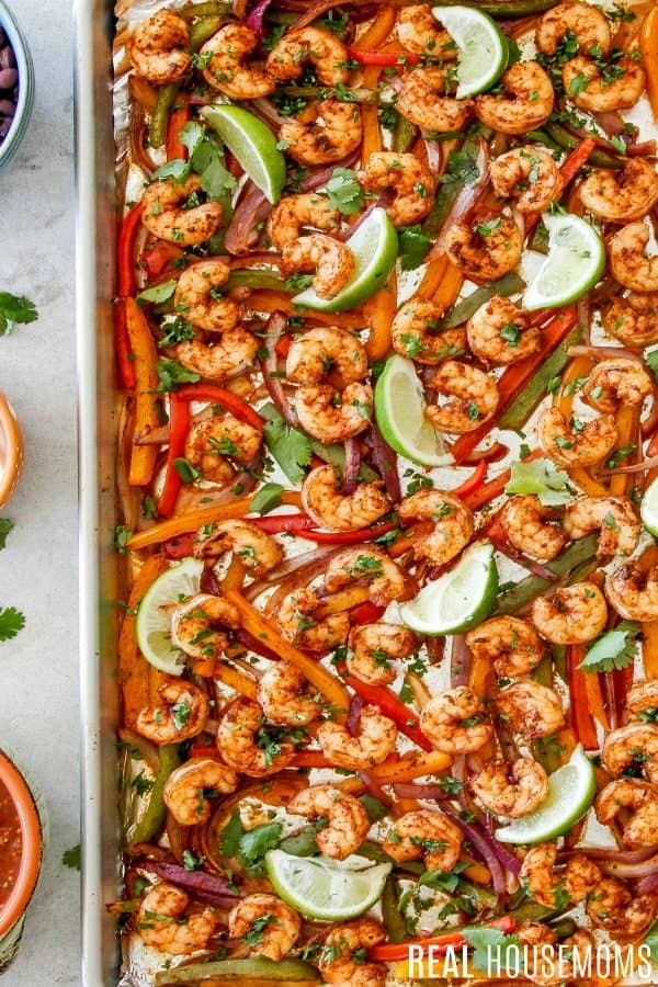 sheet pan shrimp fajitas just out of the oven served with lime wedges