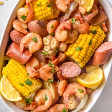 square image of shrimp boil with chopped parsley in an oval dish