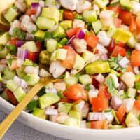 shrimp ceviche in a bowl with gold serving spoons with recipe name at the bottom