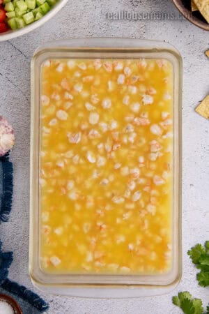chopped raw shrimp in a glass baking dish with citrus juice after chilling for 2 hours