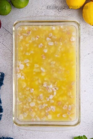 chopped raw shrimp in a glass baking dish with lime, lemon, and orange juice