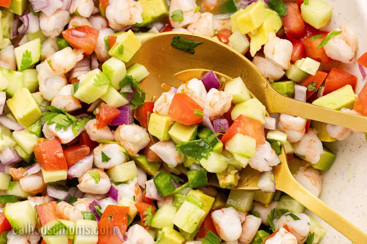 close up of serving spoons resting in a bowl of shrimp ceviche