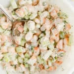 square image of shrimp salad in a bowl with a serving spoon