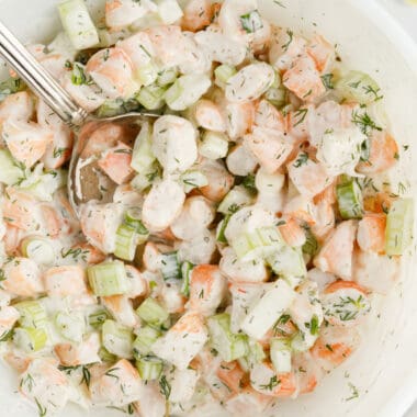 square image of shrimp salad in a bowl with a serving spoon