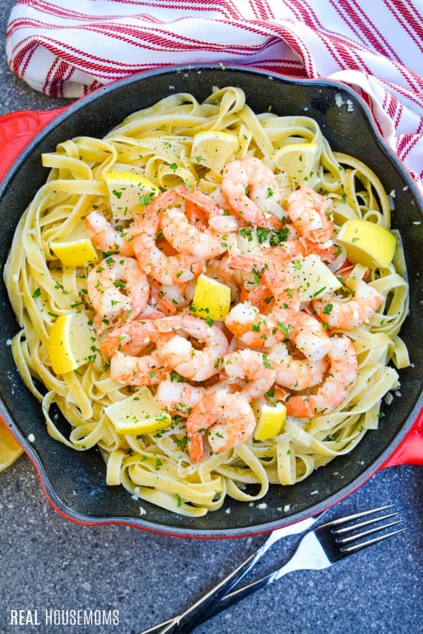 finished shrimp scampi in a skillet with pasta and garnished with lemon and parsely