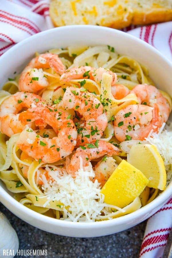 shrimp scampi in a bowl garnished with parmesan and lemons