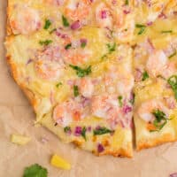 shrimp and pineapple pizza on parchment paper with recipe name at the bottom