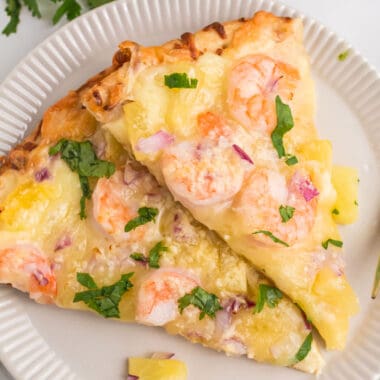 square image of two slices of shrimp and pineapple pizza on a plate