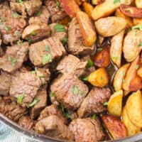 steak bites with potatoes in a deep-sided skillet with recipe name at the bottom