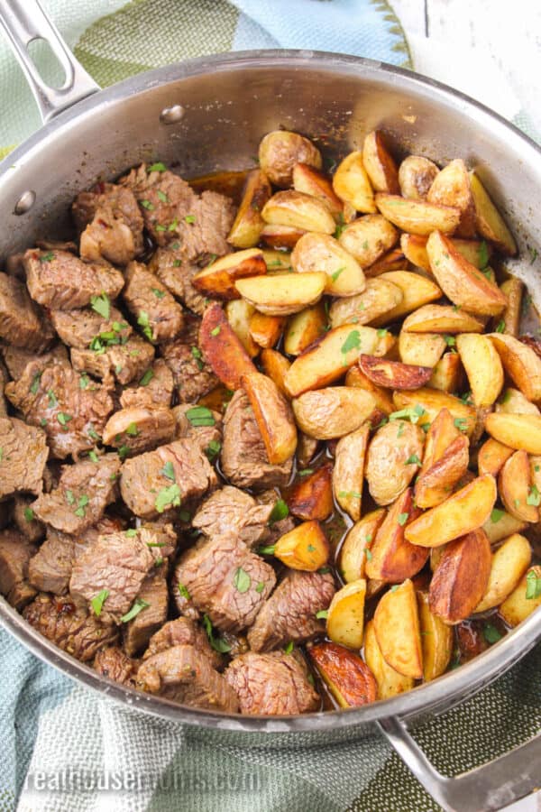 skillet steak bites with potatoes topped with chopped parsley