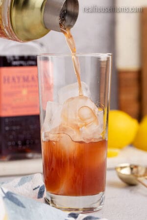 sloe gin fizz base being strained into a glass with ice