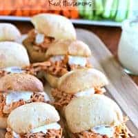 Slow Cooker Buffalo Chicken Sliders lined up on a serving board with carrots and celery