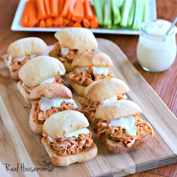 Serving platter with Slow Cooker Buffalo Chicken Sliders, extra blue cheese dressing, carrots, and celery