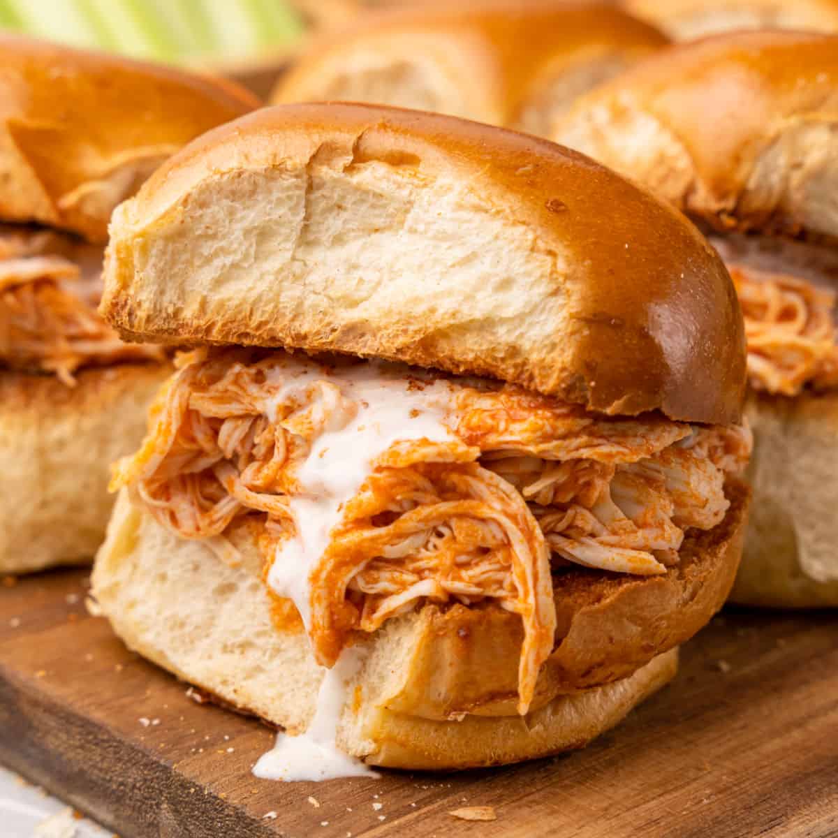square image of slow cooker buffalo chicken sliders next to carrots and celery