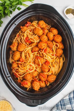 cooked spaghetti stirred into the pasta sauce, tomatoes, and meatballs