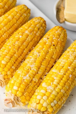 close up of slow cooker corn on the cob with salt and pepper sprinkled on top
