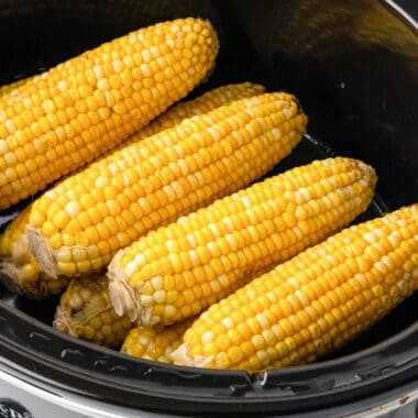 square image of slow cooker corn on the cob in a crock pot after cooking