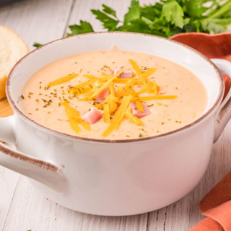 square image of slow cooker ham and potato cheese soup topped with more cheese, ham, and dried parsley