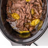slow cooker italian pepperoncini beef in a crock pot with recipe name at the bottom